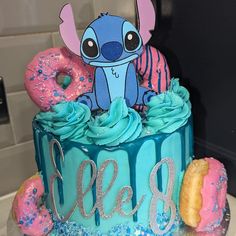 a birthday cake decorated with blue frosting and pink sprinkles, including an image of stitch