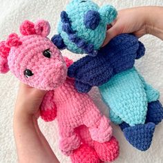 two crocheted teddy bears are being held by someone's hand