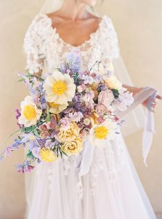 a woman holding a bouquet of flowers in her hand and wearing a white wedding dress