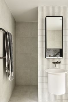 a bathroom with a sink, mirror and towel rack in it's corner next to a tiled wall