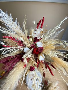 a vase filled with lots of different types of flowers and feathers on top of a table