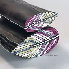 two pieces of black leather with purple and white designs on the inside are folded together