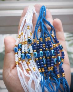 a person is holding some beads in their hand with blue and white strings on them