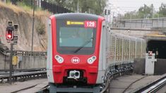 a red and white train traveling down tracks next to a tunnel on the other side