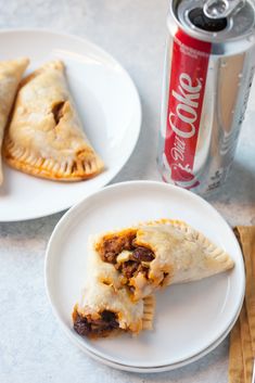 two white plates topped with pastries next to a can of coke