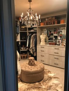 a walk in closet with an ottoman and chandelier