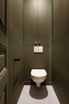 a white toilet sitting inside of a bathroom next to a wall mounted light above it