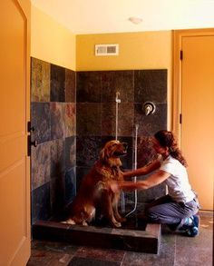 a woman is petting a dog in the shower while he sits on some steps