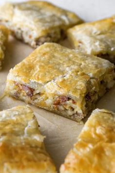 some food that is laying out on a piece of parchment paper with cheese and meat in it