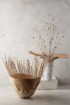 two vases sitting on top of a table next to each other with sticks sticking out of them