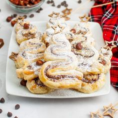 some cookies are on a white plate with chocolate chips and cinnamon sticks in the background