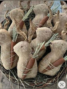 some stuffed animals are in a basket on the table with needles and grass around them