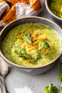 two bowls filled with broccoli and cheese soup