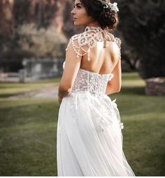 a woman in a wedding dress looking off into the distance with her back to the camera