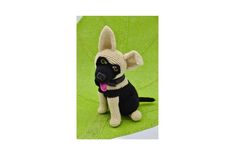 a knitted dog sitting on top of a green blanket with its tongue out and tongue out