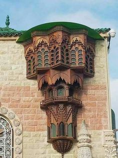 an ornate building with a green roof and window on the side of it's face