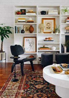 a living room filled with lots of furniture and bookshelves on top of white shelves