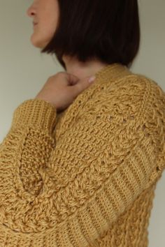 a woman is wearing a yellow sweater and has her hand on her shoulder