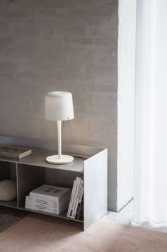 a white lamp sitting on top of a table next to a book shelf