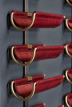 several red chairs with gold handles are lined up in a row on a gray wall