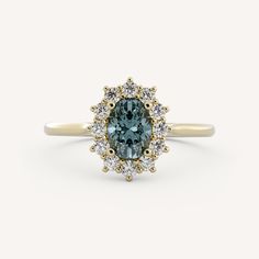 an oval blue diamond surrounded by small white diamonds on a yellow gold band, set in a halo setting