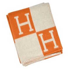 an orange and white towel with the letter h on it's front end is folded