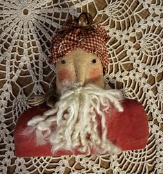 an old fashioned santa clause doll with white hair and beard sitting on a doily