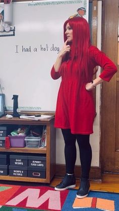 a woman with red hair standing in front of a whiteboard talking on her cell phone