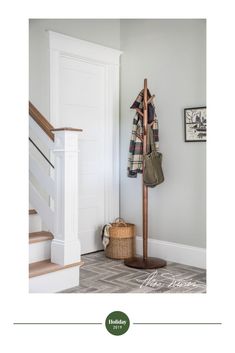 a coat rack with an umbrella hanging from it's side next to a stair case