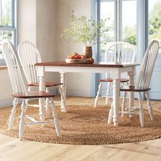 a dining room table with four chairs and a bowl of fruit on top of it