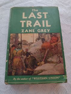 the last trail by zane grey is on a white tablecloth with an old green book cover