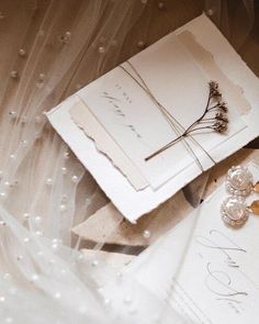 wedding stationery and rings on top of a white envelope with pearls around the edges