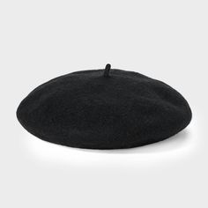 a black hat is sitting on a white surface and it's made out of wool