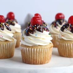 several cupcakes with white frosting and sprinkles on a plate