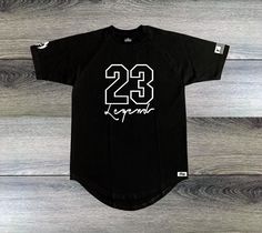 FIRE! "23 Legend" men's black and white sneaker t-shirt is the perfect complement to your Air Jordan sneakers. Designed to match popular releases like the Air Jordan Retro 11 Concord, Air Jordan 1 Retro, Air Jordan 1 High OG Black/White, Black Yeezy's, Black and white Foamposite and more, this shirt is a must-have for any sneakerhead. Made with premium cotton material and a bold sneakerhead culture graphic print, this shirt is both comfortable and stylish. Upgrade your sneaker fit with our FIRE! Black Athletic Fit T-shirt For Sports Events, Sports Season Team Name T-shirt For Streetwear, Black T-shirt For Light Sports, Athletic Fit, Black T-shirt With Graphic Print For Light Sports, Urban Black T-shirt For Sports Events, Black Athletic Fit T-shirt For Light Sports, Black Graphic Print T-shirt For Light Sports, Athletic Fit Crew Neck T-shirt For Streetwear, Black Casual T-shirt With Athletic Fit