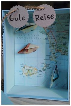 a blue box with a map and some paper boats in the front, which reads gute reise