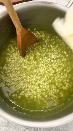 a wooden spoon stirring green liquid in a bowl