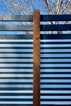 a tall wooden pole sitting next to a metal fence with trees in the back ground