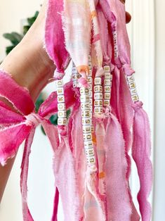 a person is holding up some pink and white pieces of fabric with words written on them