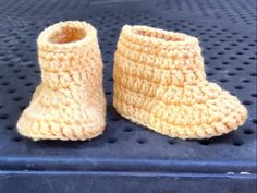 two crocheted baby booties sitting on top of a blue mat