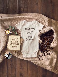 a baby's bodysuit and some coffee beans on a blanket