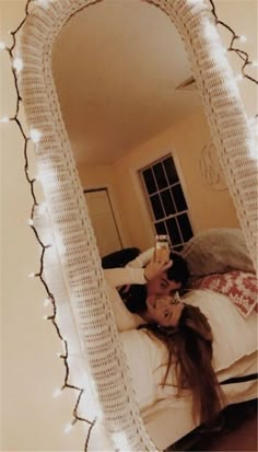 a woman laying on top of a bed under a mirror