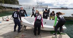 a group of people standing around a white boat