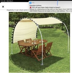 a table and chairs under an awning in the grass