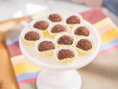 a white cake plate topped with chocolate truffles on top of a table