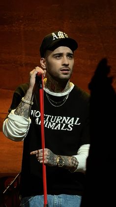 a man holding a red pole in his right hand and wearing a black shirt with white lettering on it