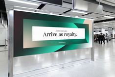 people are walking through an airport lobby with large billboards on the ceiling and in front of them, there is a sign that says arrive as royalty