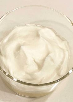 a glass bowl filled with cream on top of a table