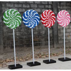 four different colored lollipops on black stands