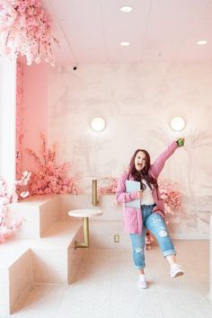 a woman is posing in front of pink flowers